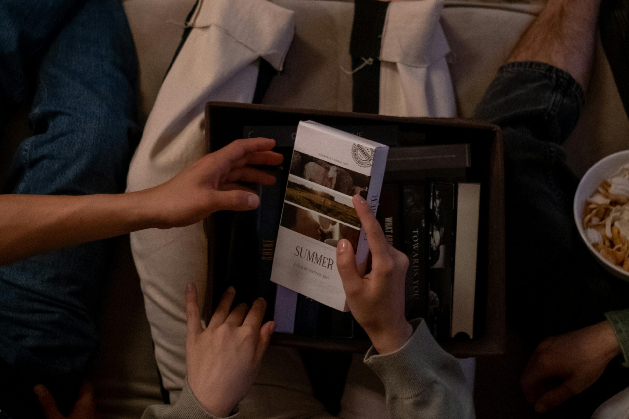 Friends enjoy a casual indoor gathering with books and snacks, sharing moments of leisure.
